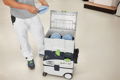 Ein handwerker steht neben einem Systainer voller Schleifmittel